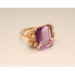 AN AMETHYST COCKTAIL RING, the rectangular cut stone claw set to open rope twist shoulders and a