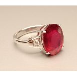 A RUBY RING, the oval mixed cut stone of 9.97cts claw set to triangular shoulders each set with a