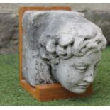 A SANDSTONE FIGURAL CORBEL, c.1900, modelled as the head of a youth, 12 3/4" x 8 1/2", on oak