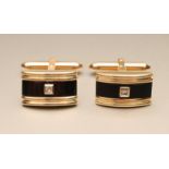 A PAIR OF 14KT GOLD CUFFLINKS, the convex oblong panels centred by onyx with a small diamond in