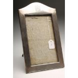 AN EDWARDIAN SILVER PHOTOGRAPH FRAME, maker's mark rubbed, Birmingham 1909, of arched oblong form