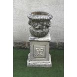 A COMPOSITION STONE URN of waisted half fluted form with ribbon tied floral swags in high relief, (