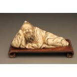 A CHINESE IVORY FIGURE carved as sleeping bearded men, his head resting on his right hand, incise