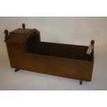 A late 19th century oak doll's cradle with (3) turned acorn surmounts, shaped inlaid hood and