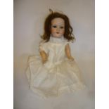 An Armand Marseille bisque head doll with blue glass sleeping eyes, open mouth and teeth, brown