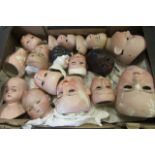 A collection of fourteen bisque doll heads, one black, some with eyes, together with a glazed