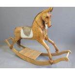 A rocking horse in carved pine, late 20th century, with inset black/amber glass eyes, leather