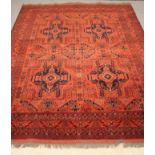 AN AFGHAN WOOL CARPET, modern, the quartered red field with four navy blue guls within geometric