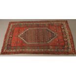 A WEST PERSIAN TRIBAL RUG, the red field with flowers and animals centred by a large lozenge