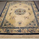 A CHINESE WASHED AND FRINGED WOOL RUG, the ivory field with emblems of immortals and central