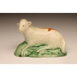 A PRATTWARE SLIP CAST SHEEP, c.1790, with an ochre cross on its back, recumbent on a green shaded