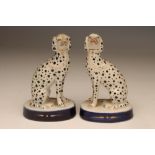 A PAIR OF LATE VICTORIAN STAFFORDSHIRE POTTERY DALMATIONS, seated with free modelled fore-legs on