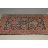 A PERSIAN RUG, the navy blue field with a bold floral pattern in red, ivory and pale green, red
