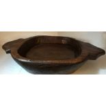 A carved two handled shallow wooden bowl. 67cms l x 38cms w