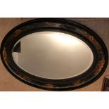 Oriental lacquer work oval mirror with bevel edged glass. 59cms x 87cms w.