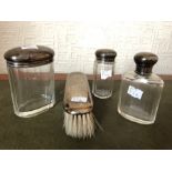 Three silver topped dressing table jars and silver backed brush.