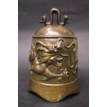 A LARGE TEMPLE BELL, with raised relief imagery of a dragon with scalloped rim, 7" tall with handle,