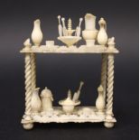 A 19TH CENTURY MINIATURE DOLL HOUSE BONE FURNITURE PIECE, a two tier table with various pieces