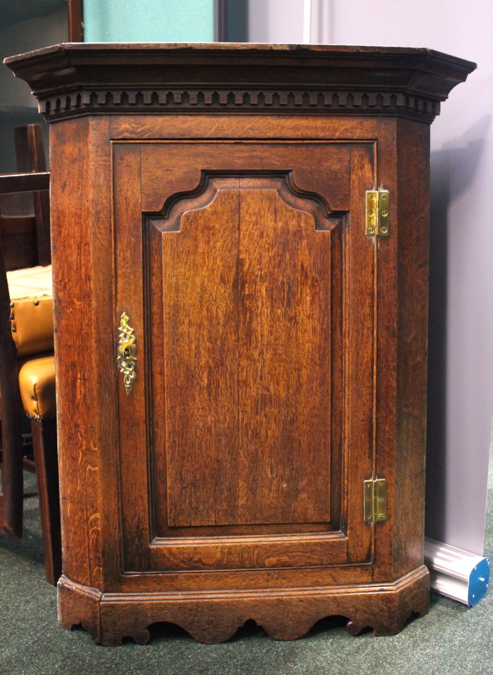 AN OAK HANGING CORNER CUPBOARD, straight fronted, with fluted cornice over a carved panel door,