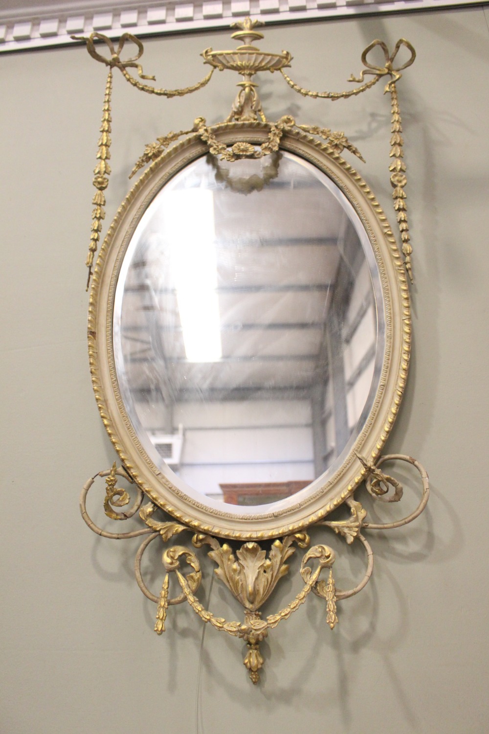 AN OVAL GILT WALL MIRROR, with floral & foliage gesso detailing, bevelled glass