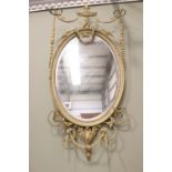 AN OVAL GILT WALL MIRROR, with floral & foliage gesso detailing, bevelled glass