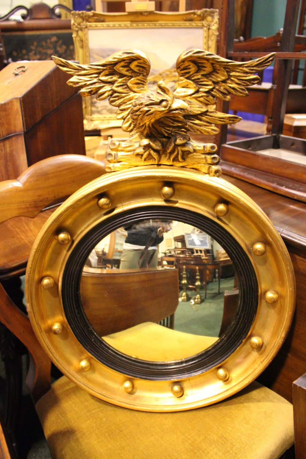 A GILT WOOD REGENCY ROUND CONVEX MIRROR, with eagle mount, ebonised reeded slip