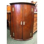 A FINE BOW FRONTED CORNER CABINET, with two doors, opening to reveal shelves within, brass key