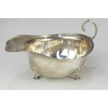 A George V Asprey silver sauce boat with flying scroll handle, on shell cast hoof feet (a/f),