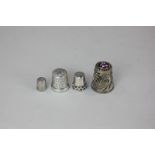 A sterling silver thimble and three other size thimbles including one with a floral enamel top