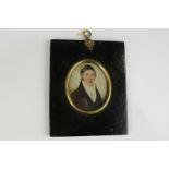 An early 19th century oval miniature portrait of a young man, in white neck cloth and black coat, on