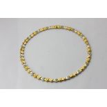 An 18ct yellow and white gold and diamond necklace strung with chevron and crescent links, the white