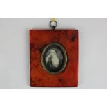 An early 19th century oval miniature portrait of a lady, resting her head on her hand, in fur