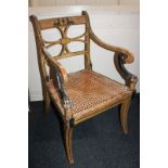 An Empire style painted wood elbow chair, with sphinx and urn decorated top rail and pierced splat