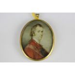 A 19th century oval miniature portrait of a gentleman, in a red tunic, on ivory, in glazed gilt