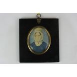 A 19th century oval miniature portrait of a lady, wearing a white bonnet and blue dress, on ivory,