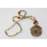 A carved and pierced jade pendant on a hardstone bead neck chain