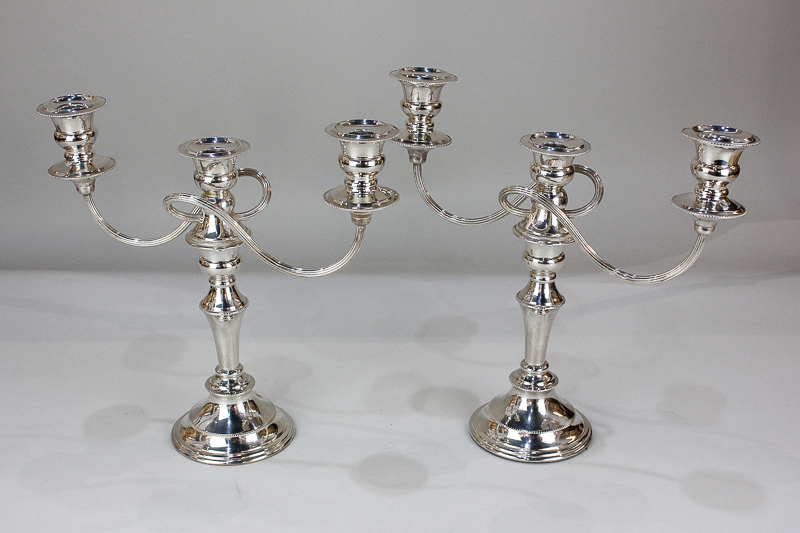 A pair of silver plated three-light candelabra with scroll branches, urn shape sconces with drip