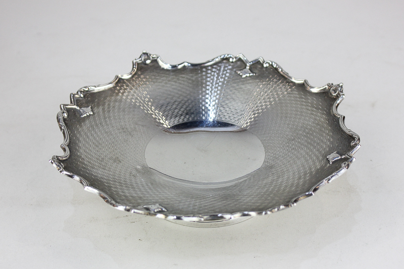 A George V silver pedestal dish with engine turned decoration and scroll border, on circular base,