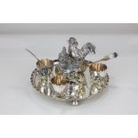 A silver plated egg stand, circular dish with central cast group of a cockerel and hen, four egg