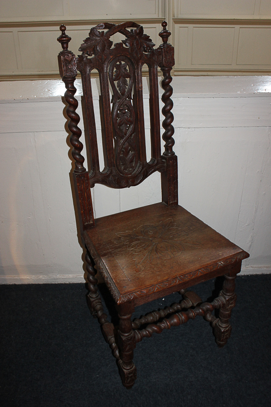 A carved oak hall chair, with foliate pierced back and floral carved hard seat, with barley twist