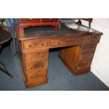 A Victorian oak pedestal desk with leather inset rectangular top and an arrangement of nine drawers,