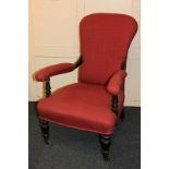 A Victorian upholstered open armchair, with ebonised frame and padded arm rests, on turned