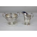 A George V silver cream jug and matching pedestal sugar bowl, with scroll handles, decorated with