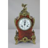 An imitation boulle mantel clock with brass scroll mounts, the circular dial with Roman and Arabic