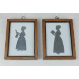 Two cut paper silhouette profile portraits, of two young ladies, holding a book and a doll, with