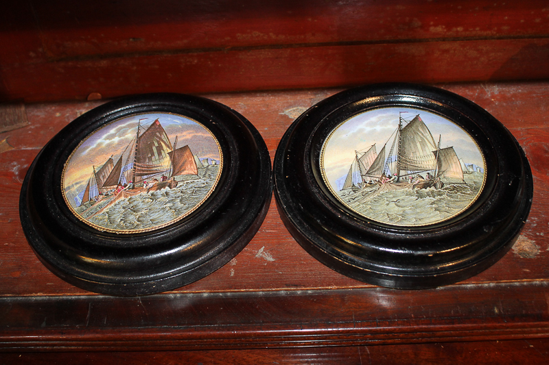 A pair of framed porcelain pot lids depicting fishing boats at sea, each lid 10cm diameter