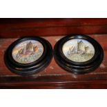 A pair of framed porcelain pot lids depicting fishing boats at sea, each lid 10cm diameter