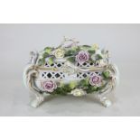 An ornate German porcelain rectangular box and cover on four scroll legs, with floral bocage