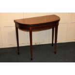 A Sheraton style mahogany demi-lune card table with fold-over green baize lined top, on square