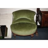 A Victorian green upholstered salon chair with shaped padded back and wide oval seat, on baluster